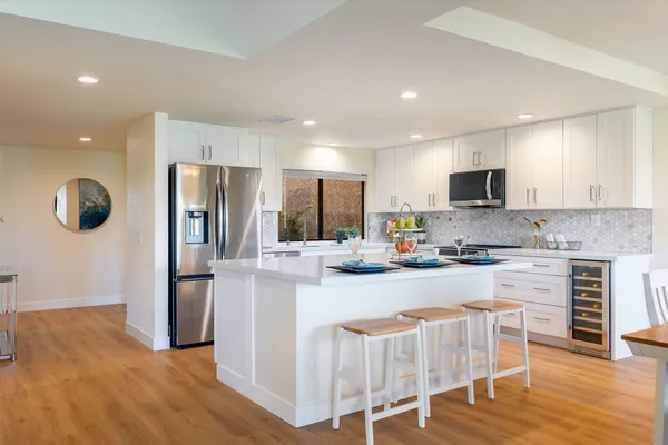 a kitchen with stainless steel appliances granite countertop a refrigerator oven a sink dishwasher and white cabinets with wooden floor