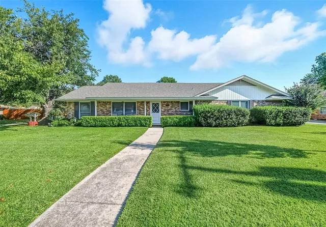 a view of house with a big yard and potted plants