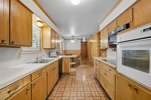 a large kitchen with stainless steel appliances a sink dishwasher a stove a refrigerator and cabinets
