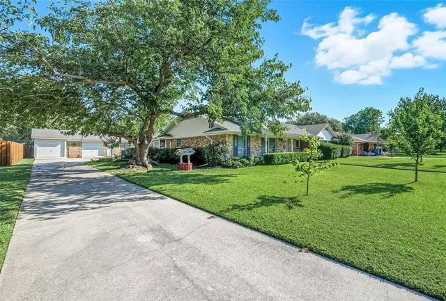 a view of a house with a big yard and large trees