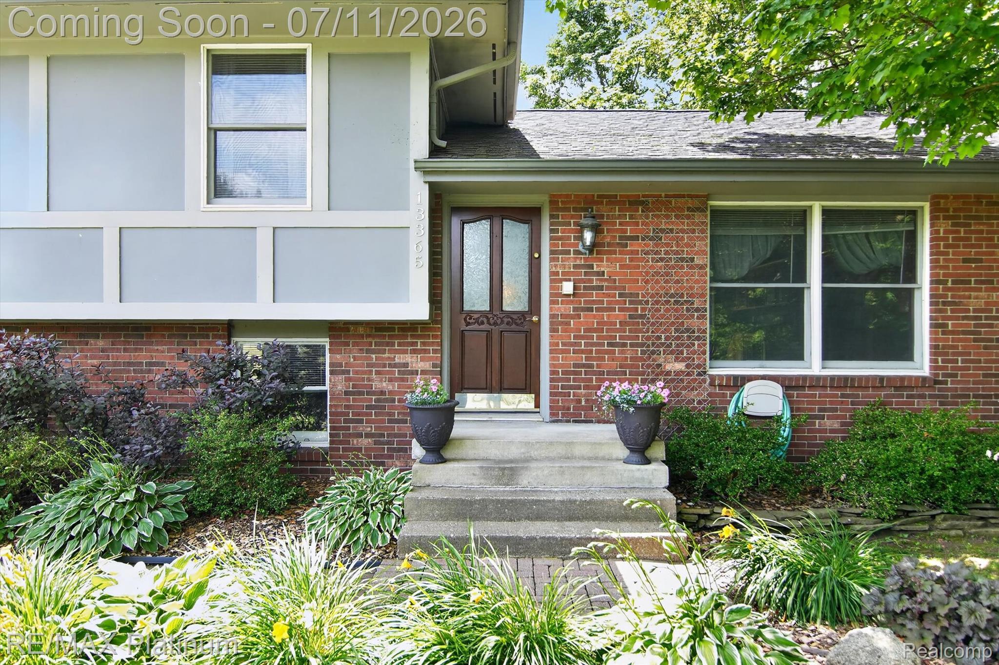 13365 North Territorial Road Gregory, MI 48137 - Photo 6 of 52 Brick and siding exterior featuring a decorative entry door with a sidelight, contrasting light gray paneling, multiple windows, and extensive perimeter landscaping