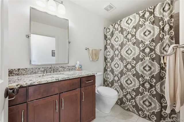a bathroom with a granite countertop sink a toilet and a mirror