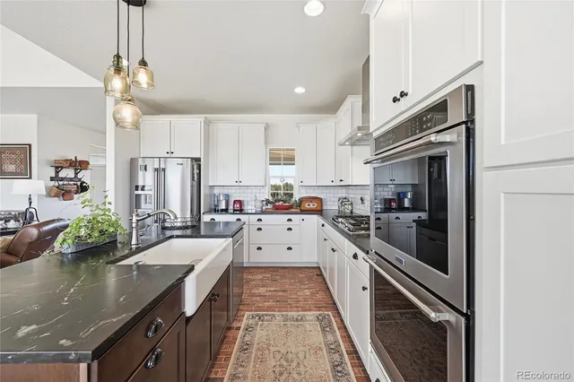 a large white kitchen with stainless steel appliances granite countertop lots of counter top space