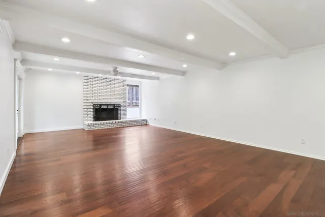 an empty room with wooden floor fireplace and window