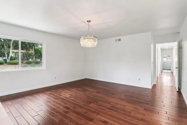 an empty room with wooden floor and ceiling fan