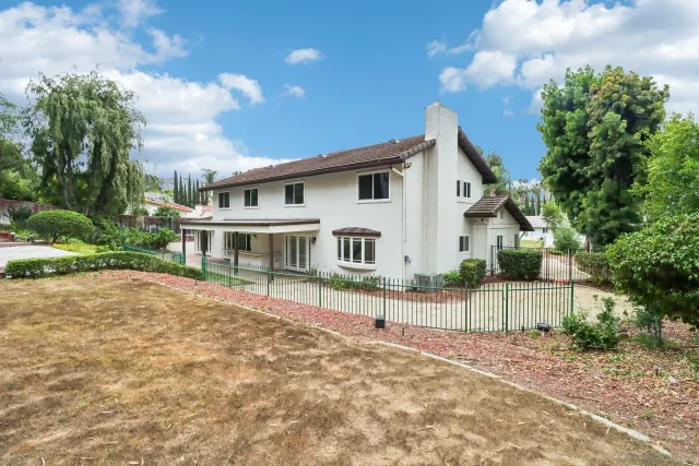 a view of a house with a yard and large tree