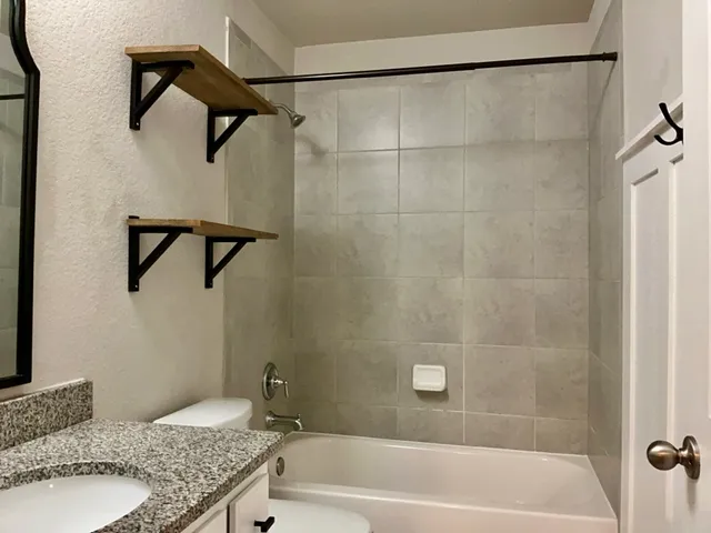 a bathroom with a granite countertop bathtub shower and vanity