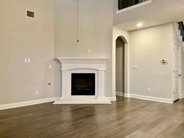 a view of an empty room with wooden floor and a fireplace