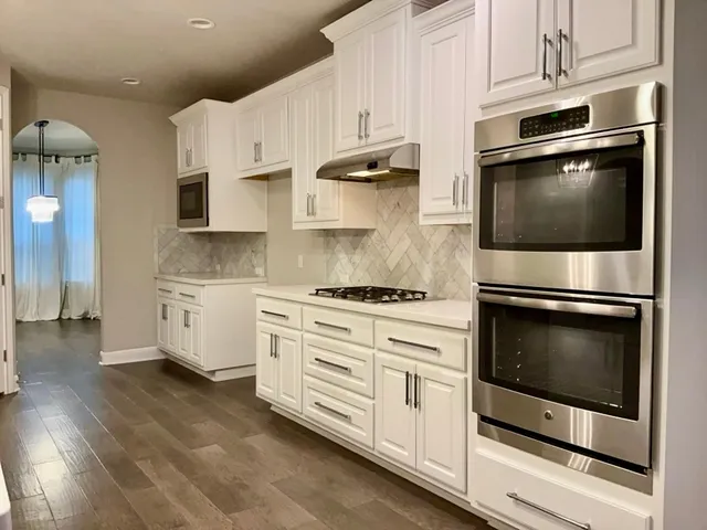 a kitchen with stainless steel appliances white cabinets and a stove a oven with white countertops