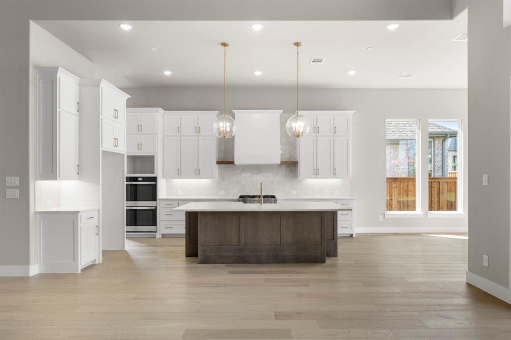 4512 Meander Way Prosper, TX 75078 - Photo 11 of 39 a large kitchen with stainless steel appliances a large counter top a stove and a sink