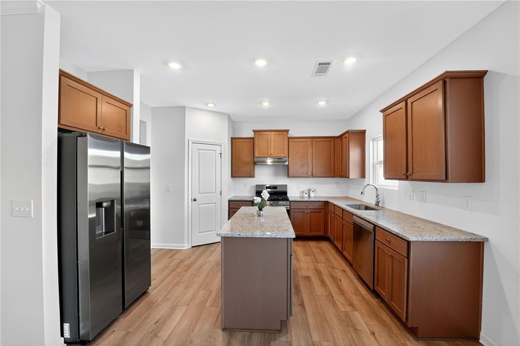 233 Bloomfield Circle Canton, GA 30114 - Photo 3 of 22 a large kitchen with stainless steel appliances granite countertop a refrigerator a sink dishwasher and wooden cabinets with wooden floor