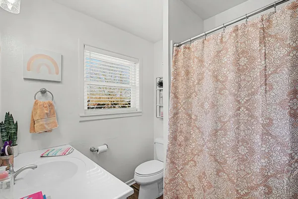 a white toilet sitting next to a white sink and a shower curtain