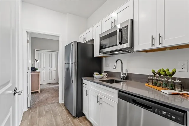 a kitchen with stainless steel appliances a sink a microwave refrigerator and cabinets