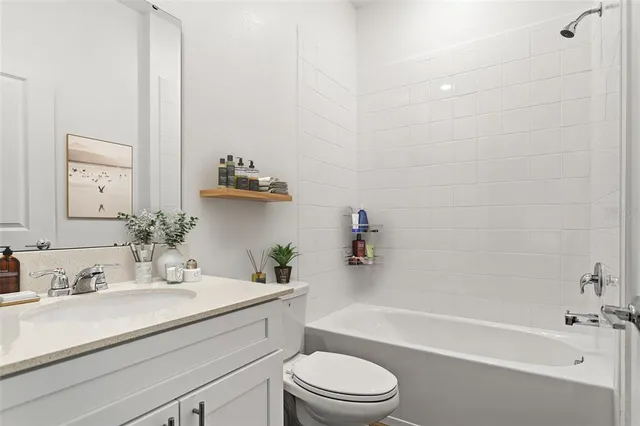 a bathroom with a granite countertop bathtub shower sink vanity mirror and toilet