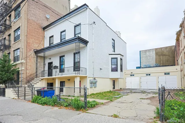 a view of a white house with large windows and a small yard
