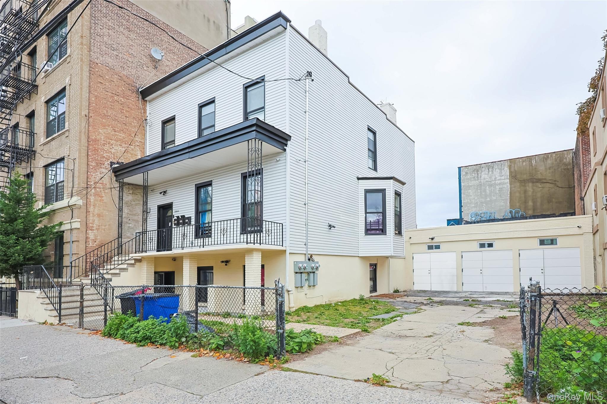 2064 Bathgate Avenue Bronx, NY 10457 - Photo 2 of 14 a view of a white house with large windows and a small yard