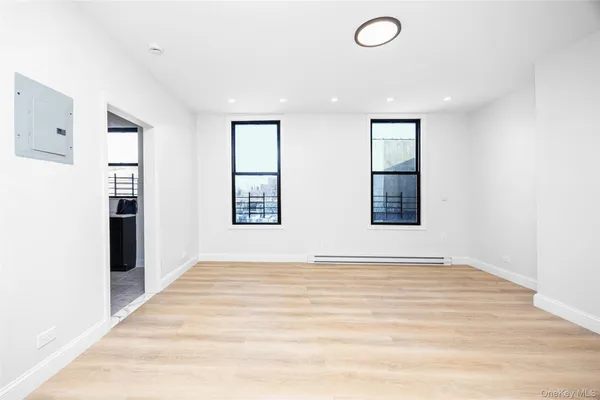 a view of an empty room with window and wooden floor