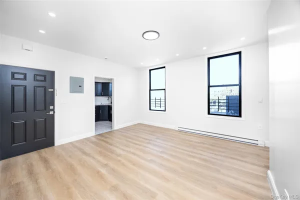 a view of an empty room with window and wooden floor