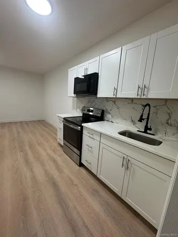 a kitchen with stainless steel appliances granite countertop a sink a stove and a microwave