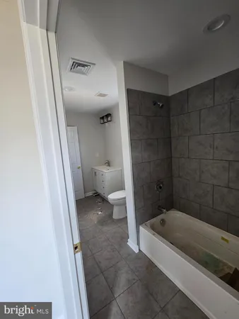 a bathroom with a granite countertop bathtub shower and toilet