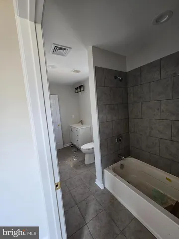 a bathroom with a granite countertop bathtub shower and toilet