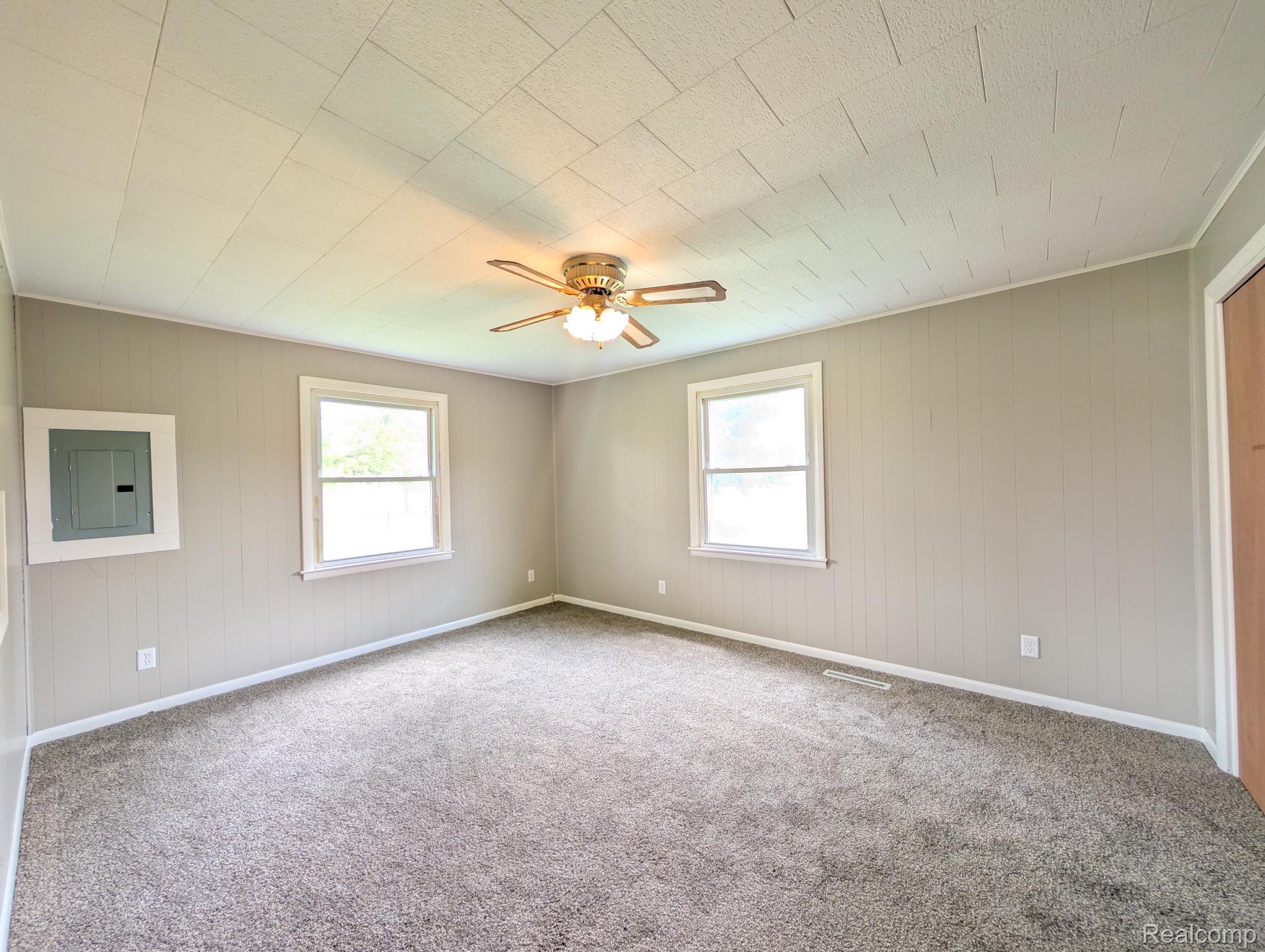 7032 Neff Road Mount Morris, MI 48458 - Photo 10 of 20 Carpeted spare room featuring electric panel, plenty of natural light, wooden walls, and a ceiling fan