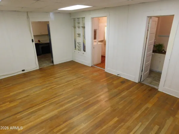 a view of an empty room with wooden floor and a bathroom