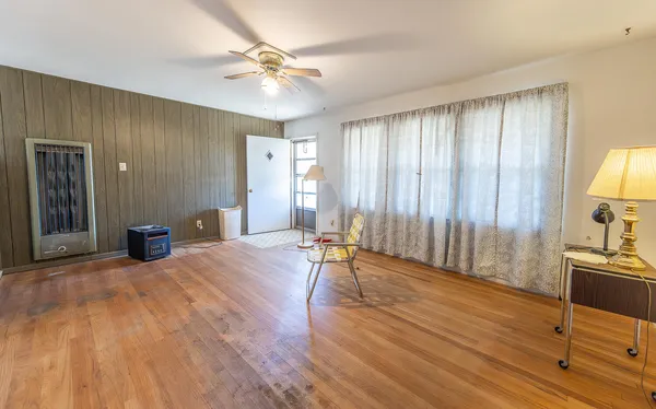 a view of an empty room with window and wooden floor