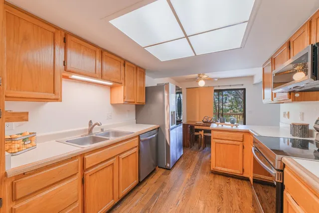 a kitchen with stainless steel appliances granite countertop wooden cabinets a sink stove and refrigerator