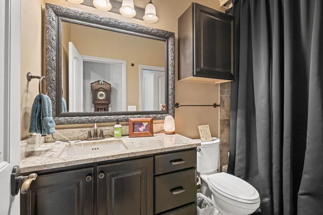 a bathroom with a granite countertop sink vanity mirror and toilet