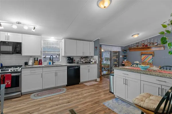 a kitchen with stainless steel appliances granite countertop a stove a sink dishwasher and a refrigerator with wooden floor