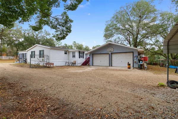 a view of a house with a yard and large trees