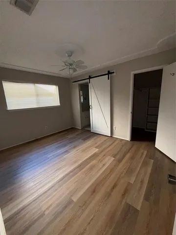 a view of empty room with wooden floor and fan