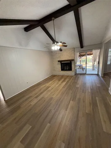 an empty room with wooden floor a ceiling fan and windows