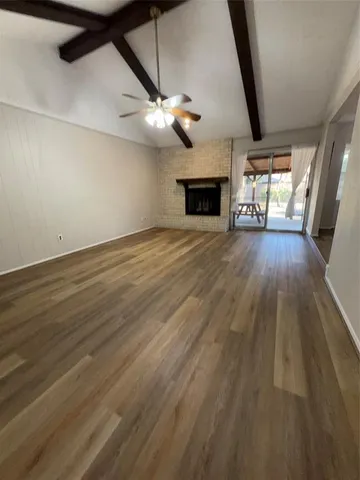 an empty room with wooden floor ceiling fan and windows