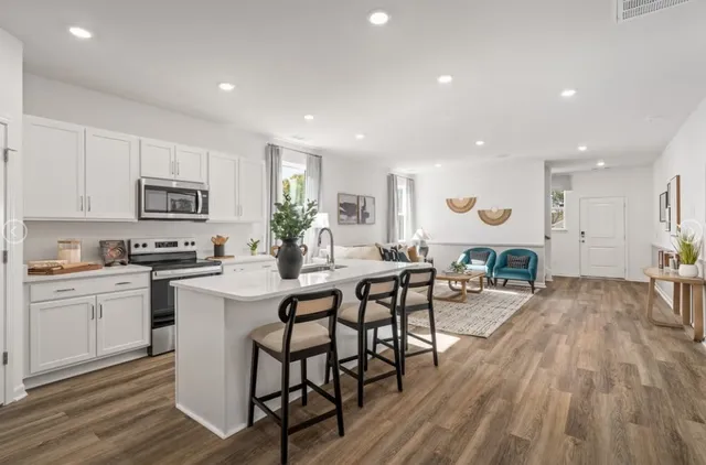 a kitchen with stainless steel appliances granite countertop a stove top oven a sink dishwasher a dining table and chairs with wooden floor