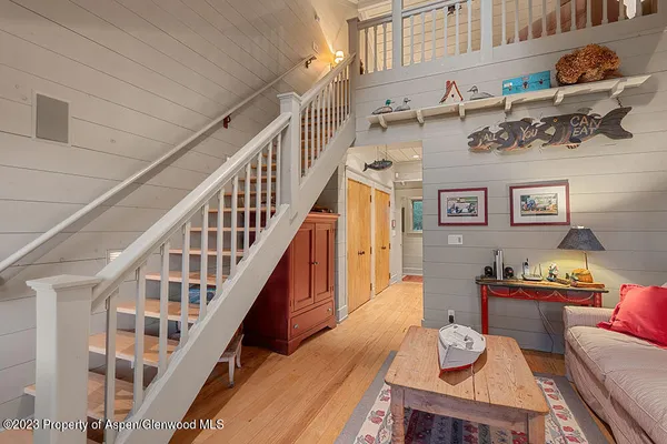 a view of a livingroom with furniture stairs wooden floor and windows