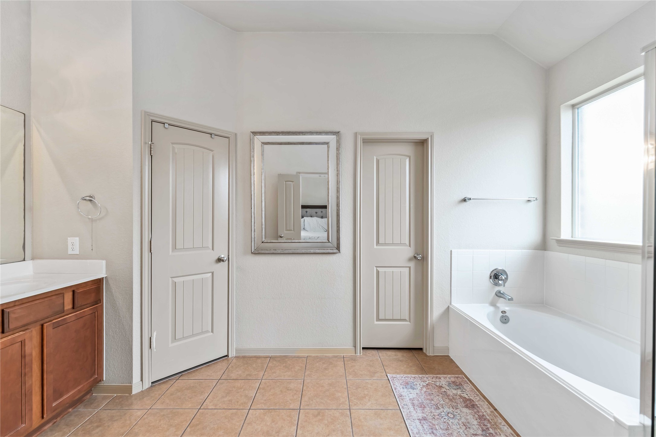 2502 Tiger Eye Drive Rosharon, TX 77583 - Photo 14 of 29 This bathroom features a spacious layout with a large bathtub, a private water room, a walk in closet, and a vanity with wood cabinetry. It has a neutral color palette, tiled flooring, and a high ceiling for an airy feel.