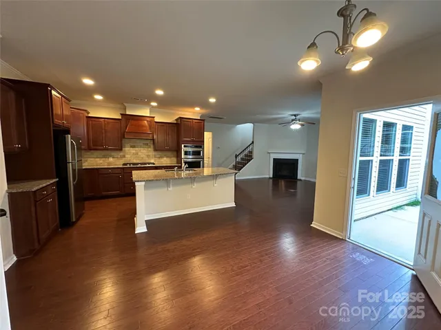 a view of a living room with wooden floor and a kitchen