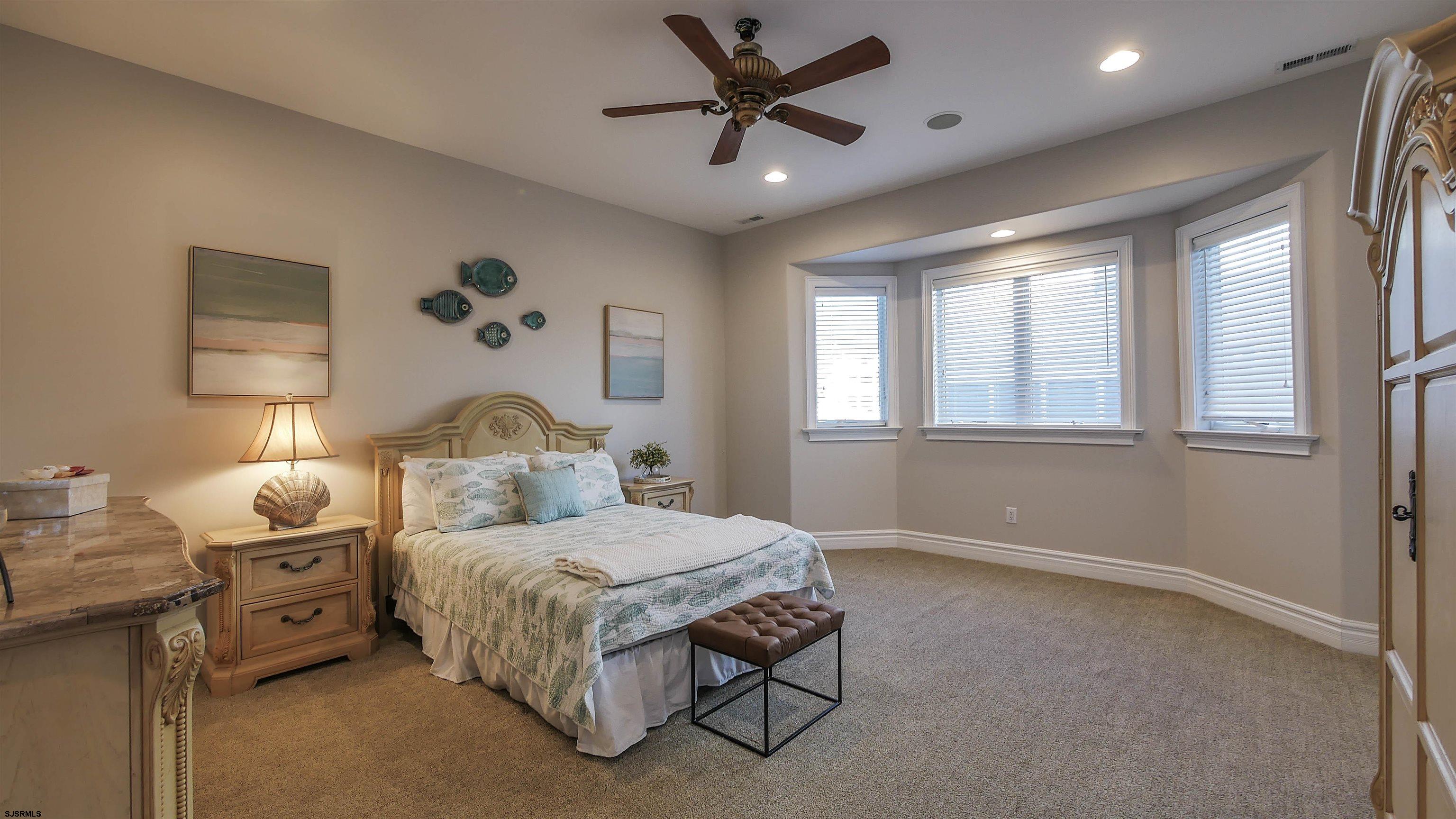 530 West Shore Drive, Unit DIRECT BAYFRONT Brigantine, NJ 08203 - Photo 19 of 63 a bedroom with a bed and a chandelier