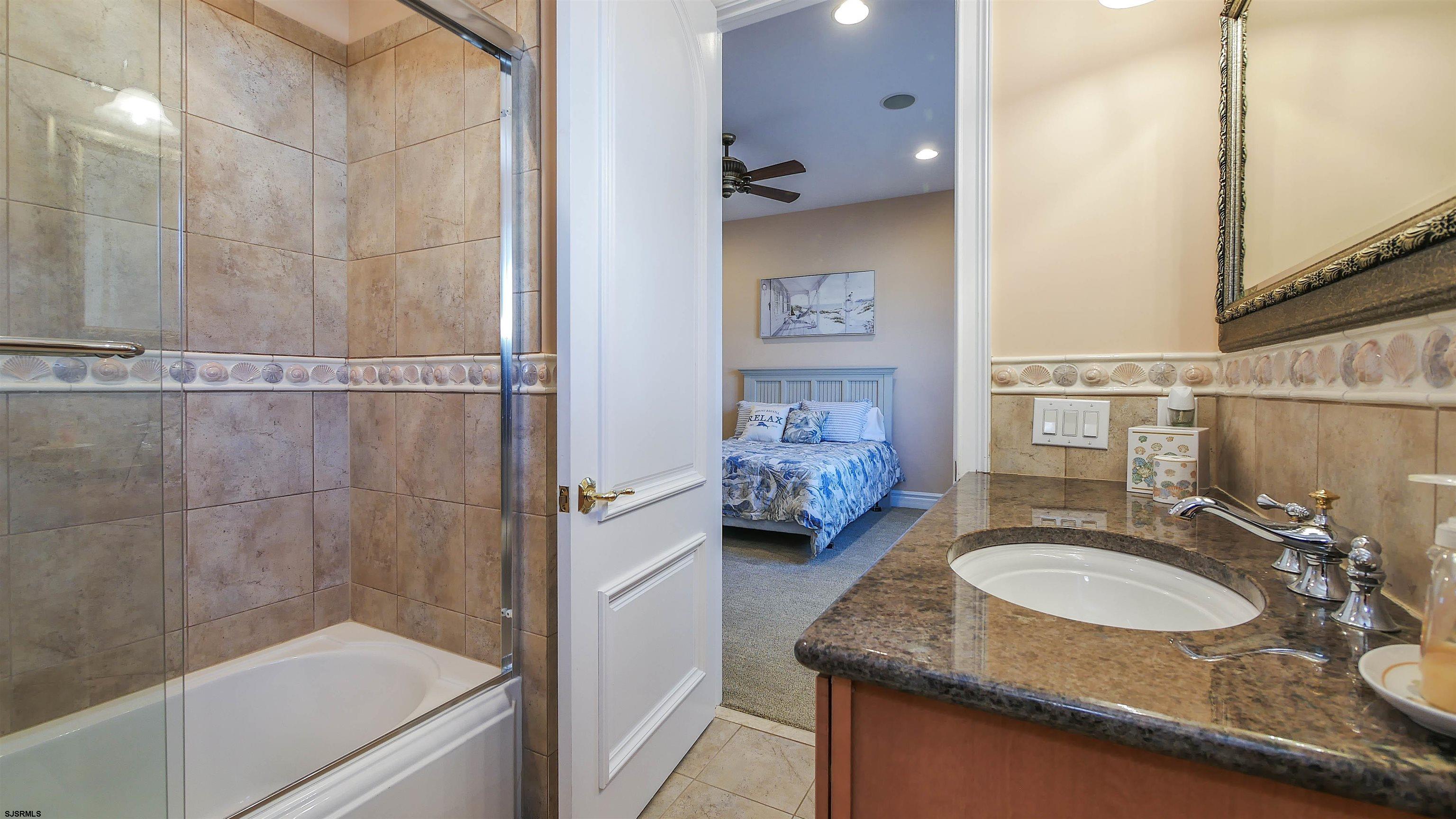 530 West Shore Drive, Unit DIRECT BAYFRONT Brigantine, NJ 08203 - Photo 40 of 63 a bathroom with a granite countertop sink a mirror and shower