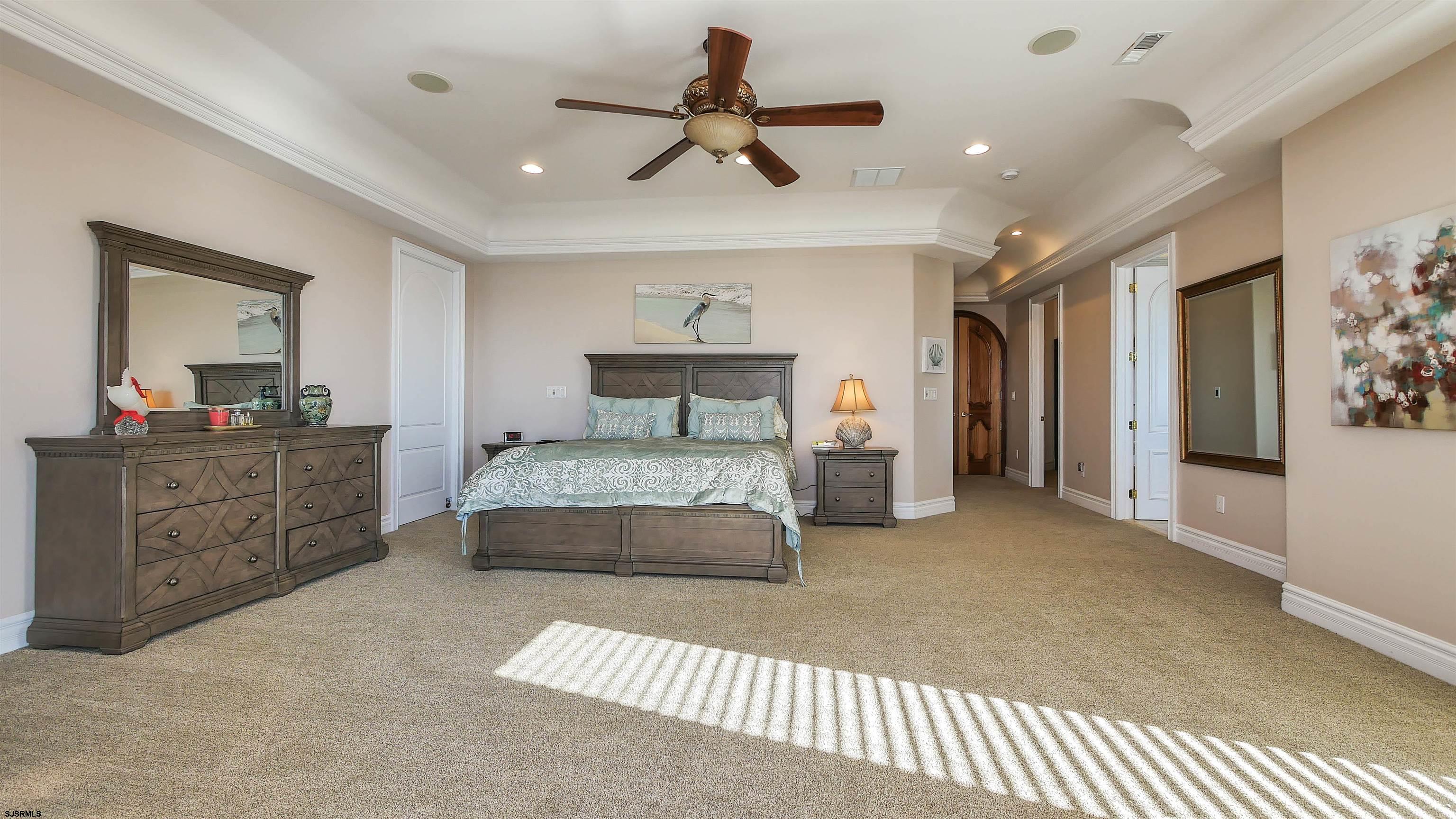 530 West Shore Drive, Unit DIRECT BAYFRONT Brigantine, NJ 08203 - Photo 43 of 63 a bedroom with a large bed and a chandelier