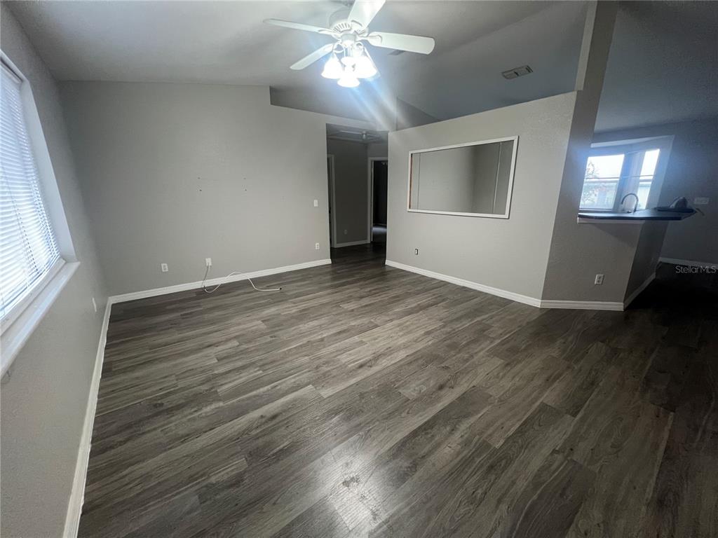 6070 Southwest 99th Place Ocala, FL 34476 - Photo 11 of 19 an empty room with wooden floor fan and windows