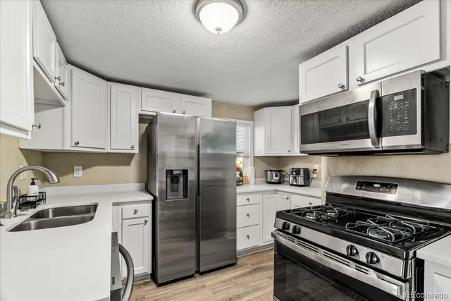 a kitchen with stainless steel appliances a refrigerator a stove top oven a sink and cabinets