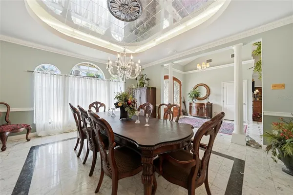 a view of a dining room and livingroom with furniture a chandelier and a rug