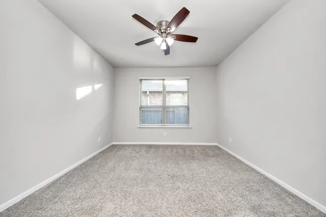 an empty room with windows and ceiling fan