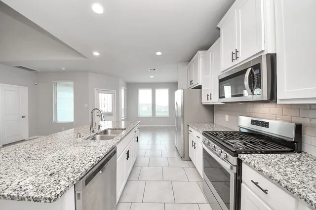 a kitchen with stainless steel appliances granite countertop a sink stove and cabinets