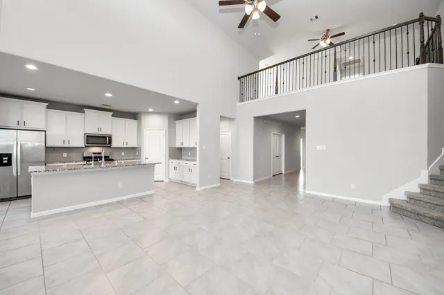 a view of kitchen with refrigerator and white cabinets