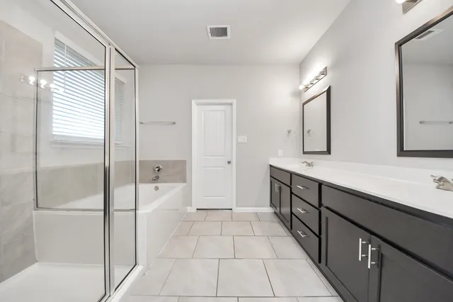 a spacious bathroom with a shower and a double vanity sink mirror