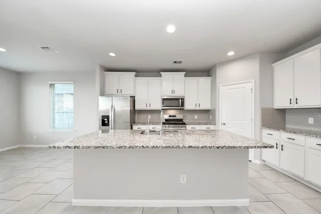 a large kitchen with granite countertop a large counter top stainless steel appliances and cabinets